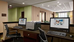 A hotel business center with two desktop computers, a printer, and a laptop.