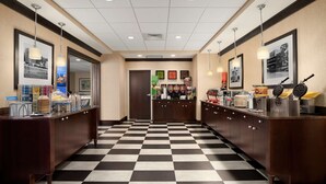 A hotel lobby with checkered flooring, a reception desk, and framed pictures on the walls.