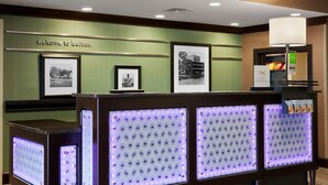 A reception area with a 'Welcome to Belton' sign, framed black and white photos, and illuminated light panels.