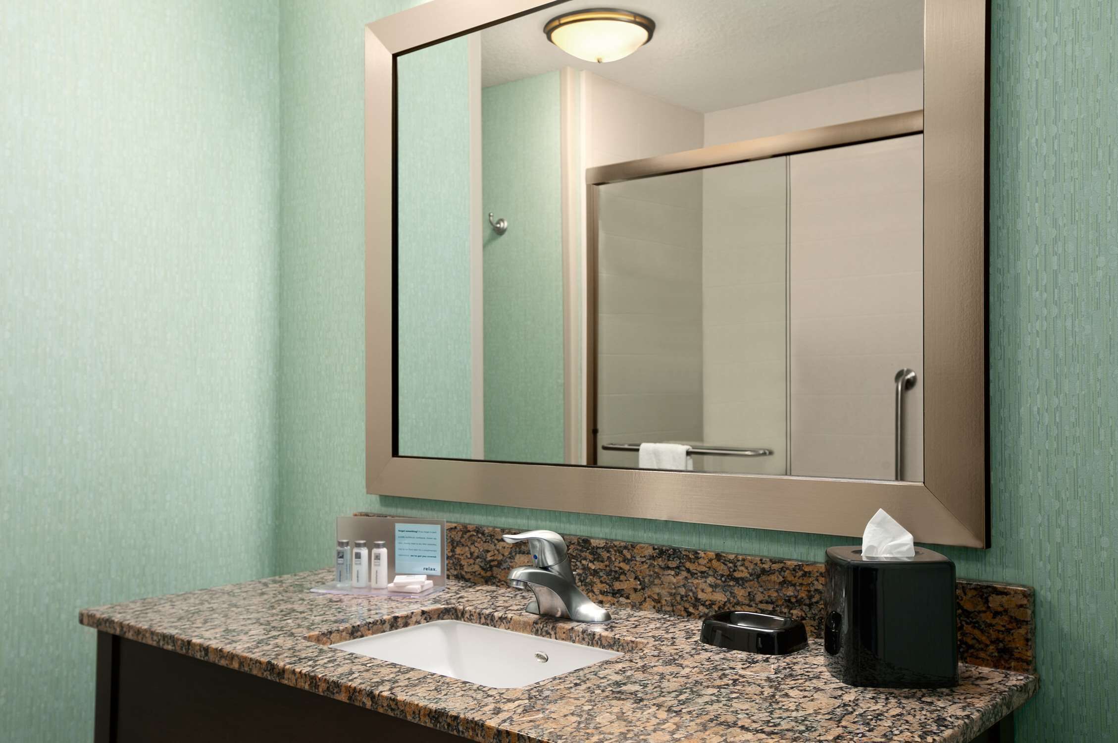 A bathroom with a granite countertop, a sink, a mirror, and a towel rack.