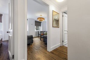 A modern interior with a wooden floor, a dining area with a table and chairs, and a large mirror on the wall.