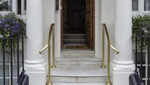 A building entrance with a sign reading "44CVRZONST" and a set of marble steps with brass railings. - Curzon Street by Mansley (London)