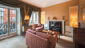A living room with a fireplace, sofa, and television. - Curzon Street by Mansley (London)