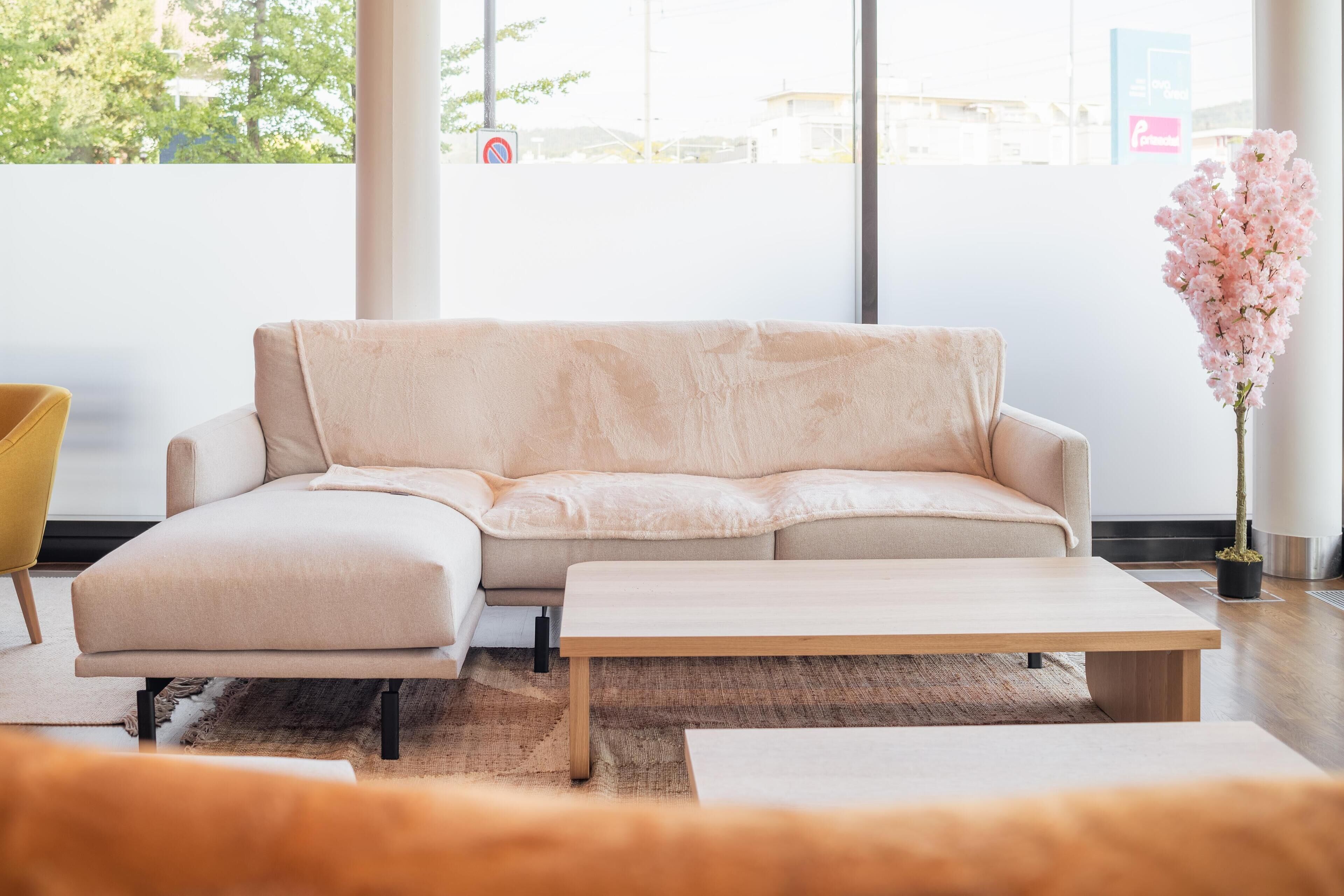 A modern living room with a beige sofa, a wooden coffee table, and a yellow chair.