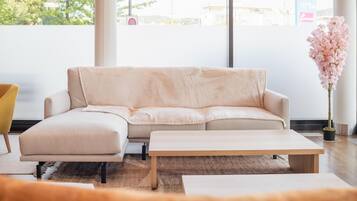 A modern living room with a beige sofa, a wooden coffee table, and a yellow chair.