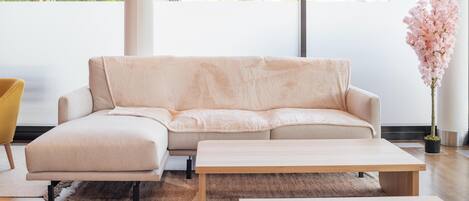 A modern living room with a beige sofa, a wooden coffee table, and a yellow chair.