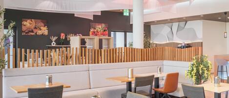 A modern restaurant with booths and tables, wooden partitions, and decorative plants.