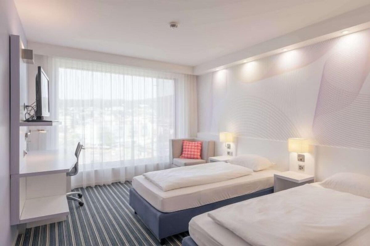 A hotel room with two beds, a desk, and a chair.