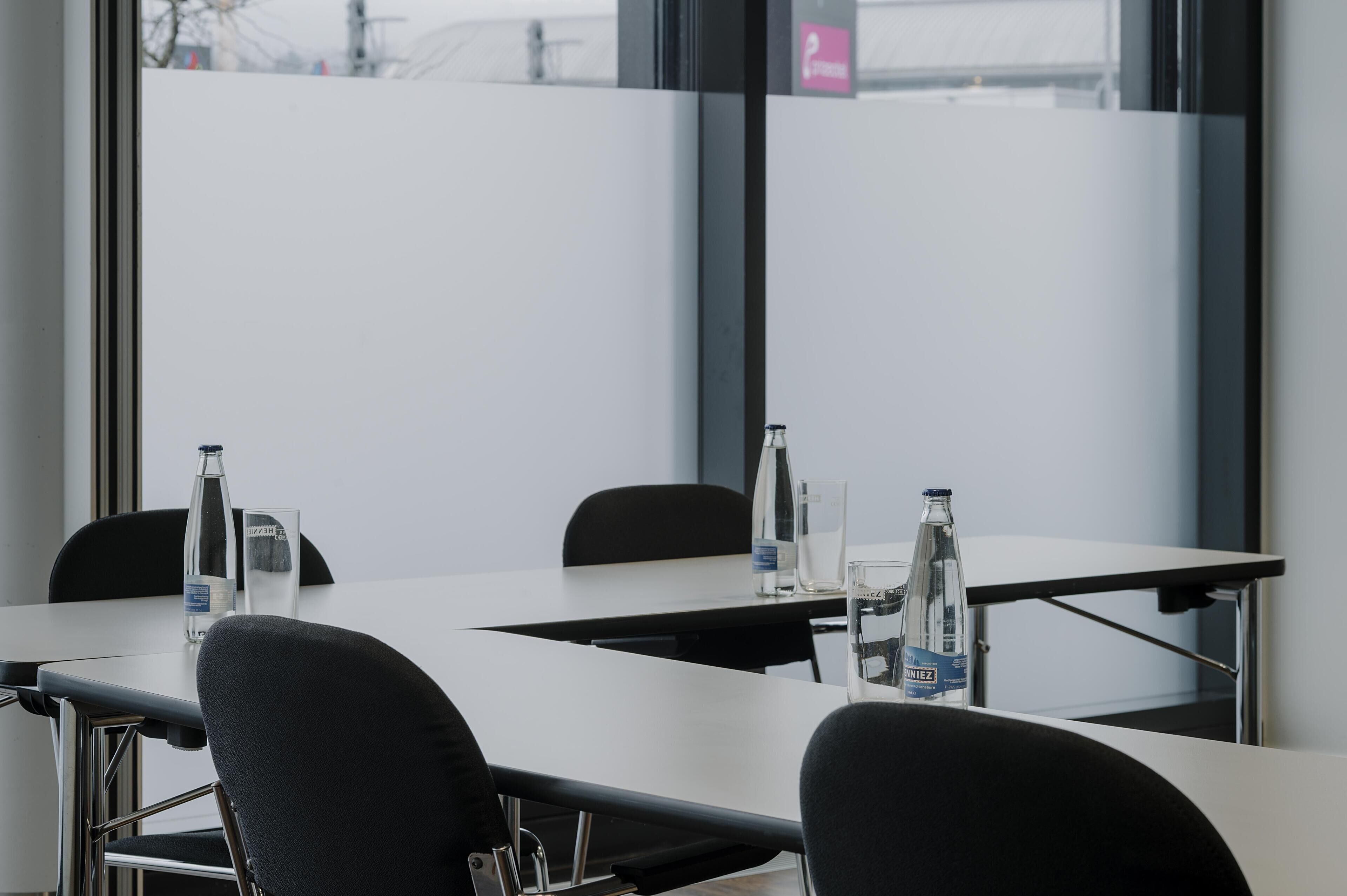A conference room with a white table, black chairs, and water bottles.