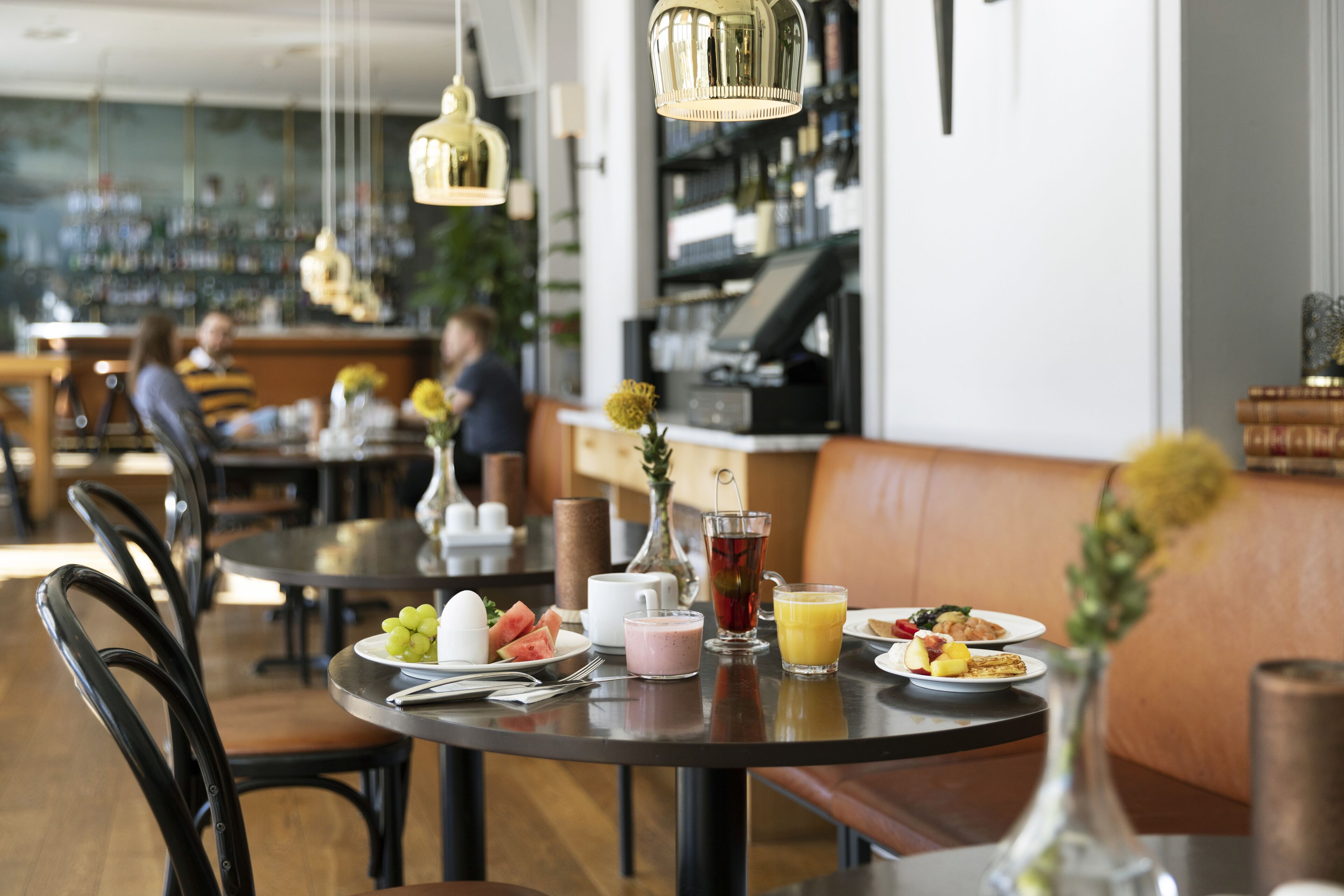 Un restaurante con mesas redondas, sillas y una zona de bar al fondo.