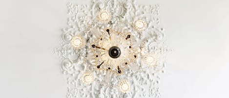 A ceiling with a central chandelier surrounded by ornate, symmetrical patterns.