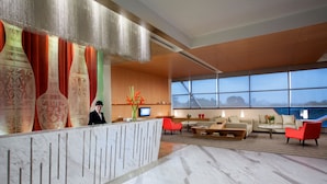 A modern lobby with a reception desk, seating area, and large windows offering a view. - Citadines Uplands Kuching (Kuching)