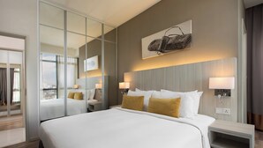 A hotel room with a large bed, two bedside tables with lamps, a mirror, and a wall-mounted artwork. - Citadines Uplands Kuching (Kuching)