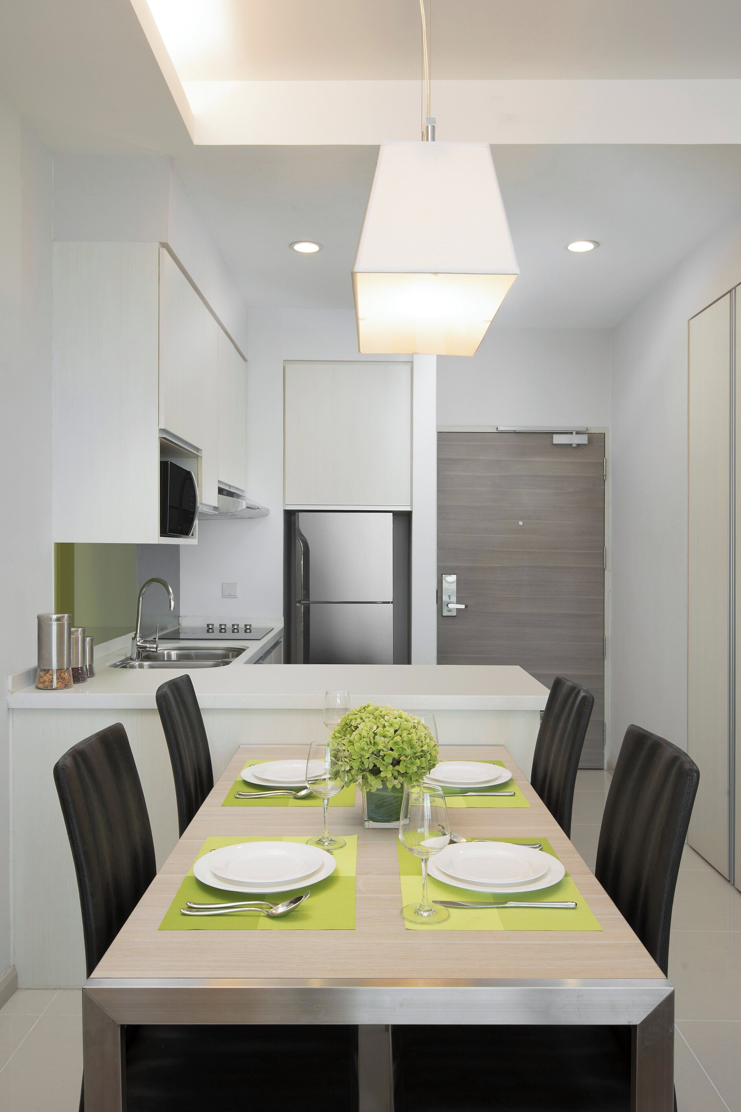Una cocina moderna con comedor, que incluye un refrigerador de acero inoxidable, un microondas y un lavamanos.