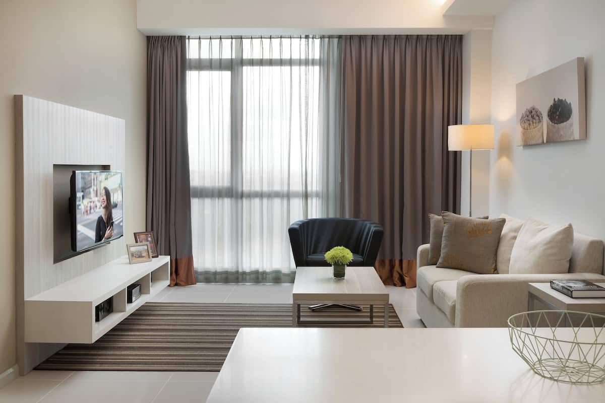 A modern living room with a flat-screen TV, a sofa, a coffee table, and a lamp.
