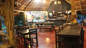 Un restaurant intérieur avec des tables et des bancs en bois, un bar et un tableau affichant le menu.