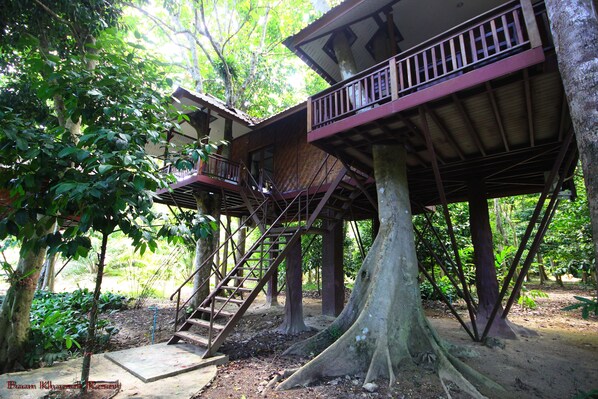 Une cabane dans les arbres avec un escalier en bois et un balcon.