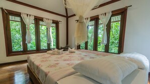 Une chambre avec un grand lit, un plancher en bois et des fenêtres avec des rideaux.