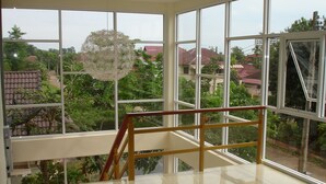 A spacious room with large windows, a wooden railing, and a hanging light fixture. - Green Home Resort (Surat Thani)