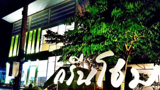 A building with a large illuminated sign, surrounded by greenery. - Green Home Resort (Surat Thani)