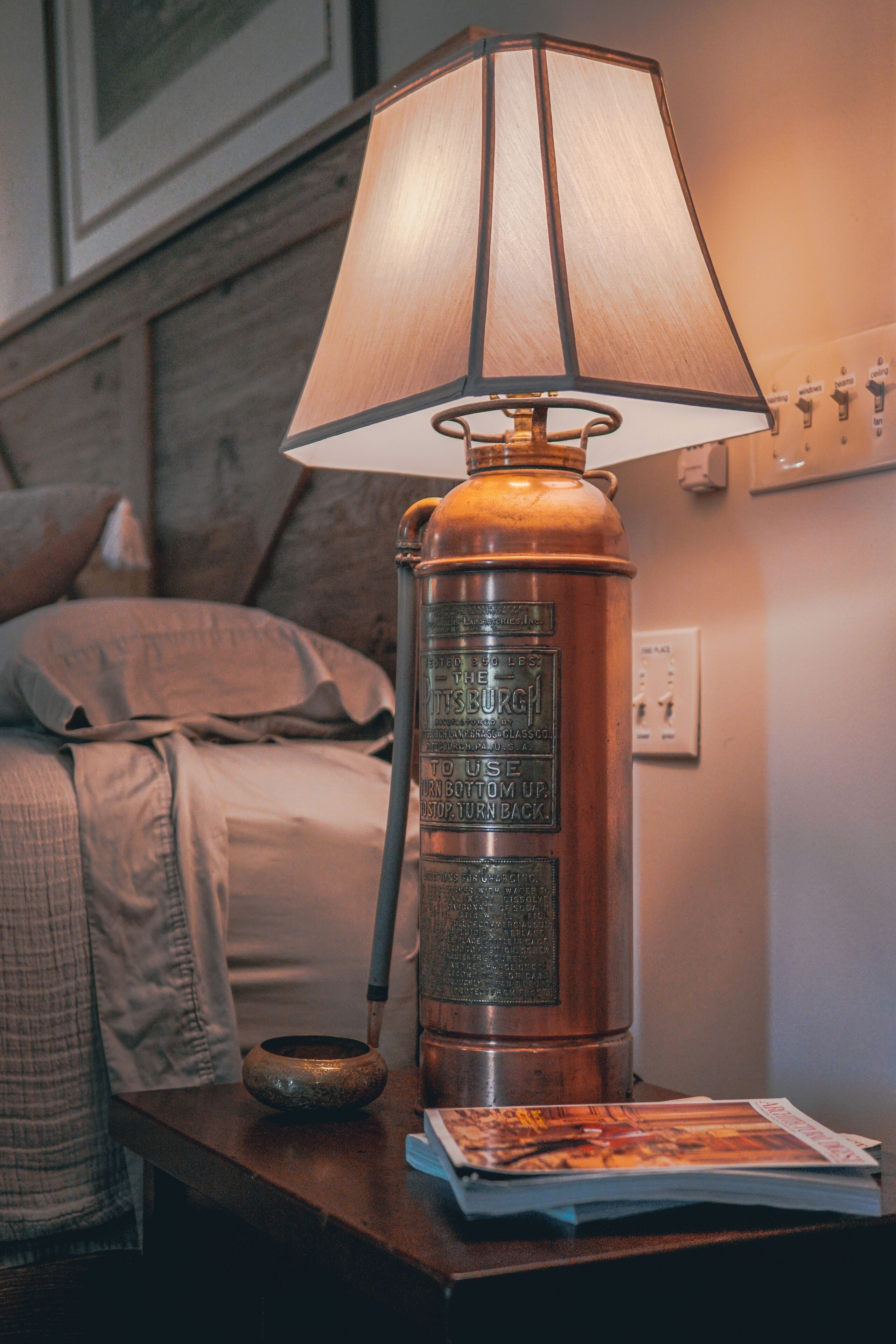 A vintage-style lamp with a metal base and a fabric shade on a bedside table.