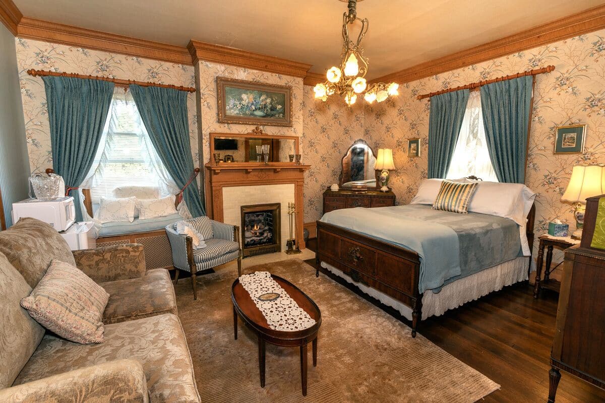 Quarto tradicional com lareira, cama, sofá e um candelabro.