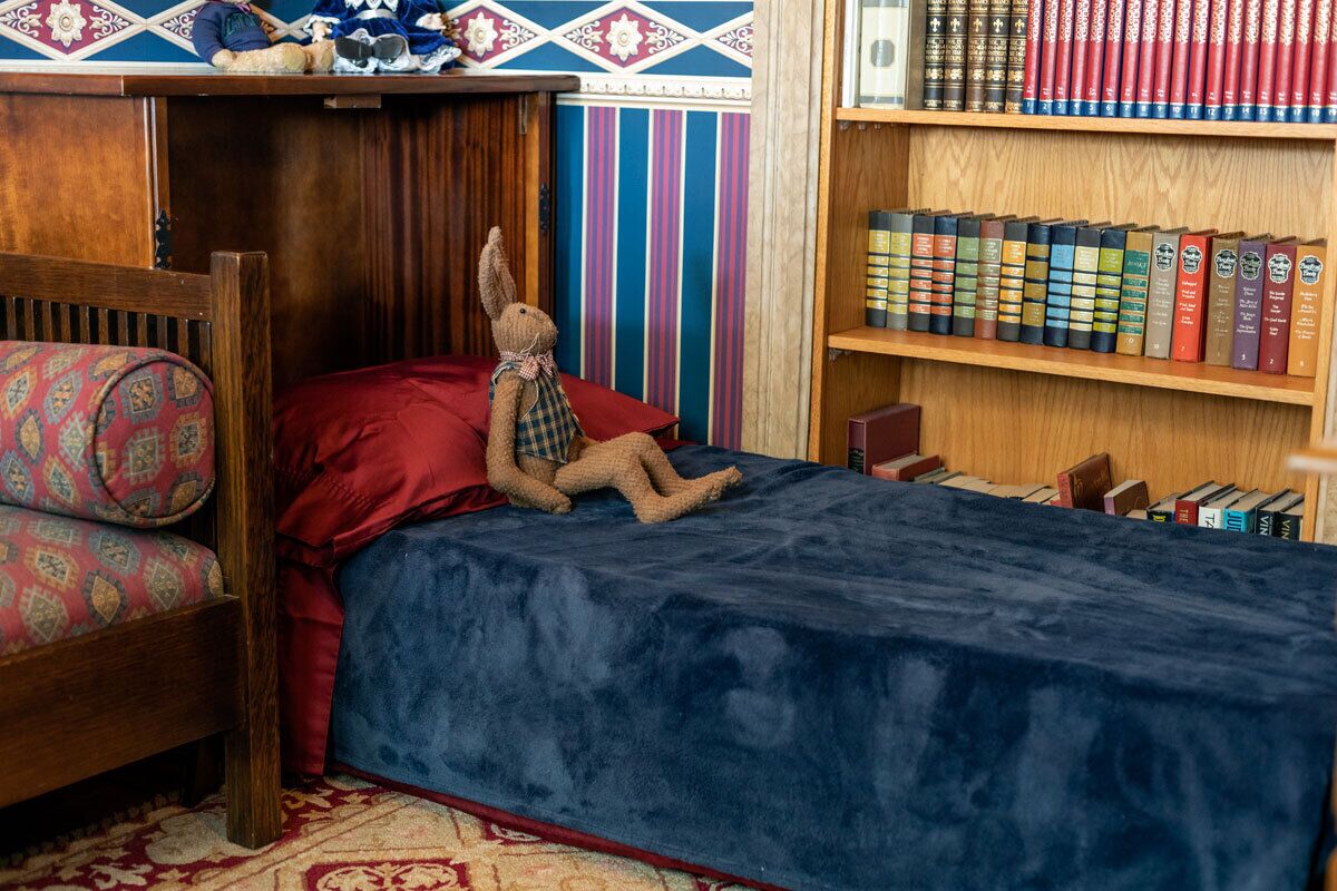 A cozy room with a bed, a small table, and a bookshelf filled with books.