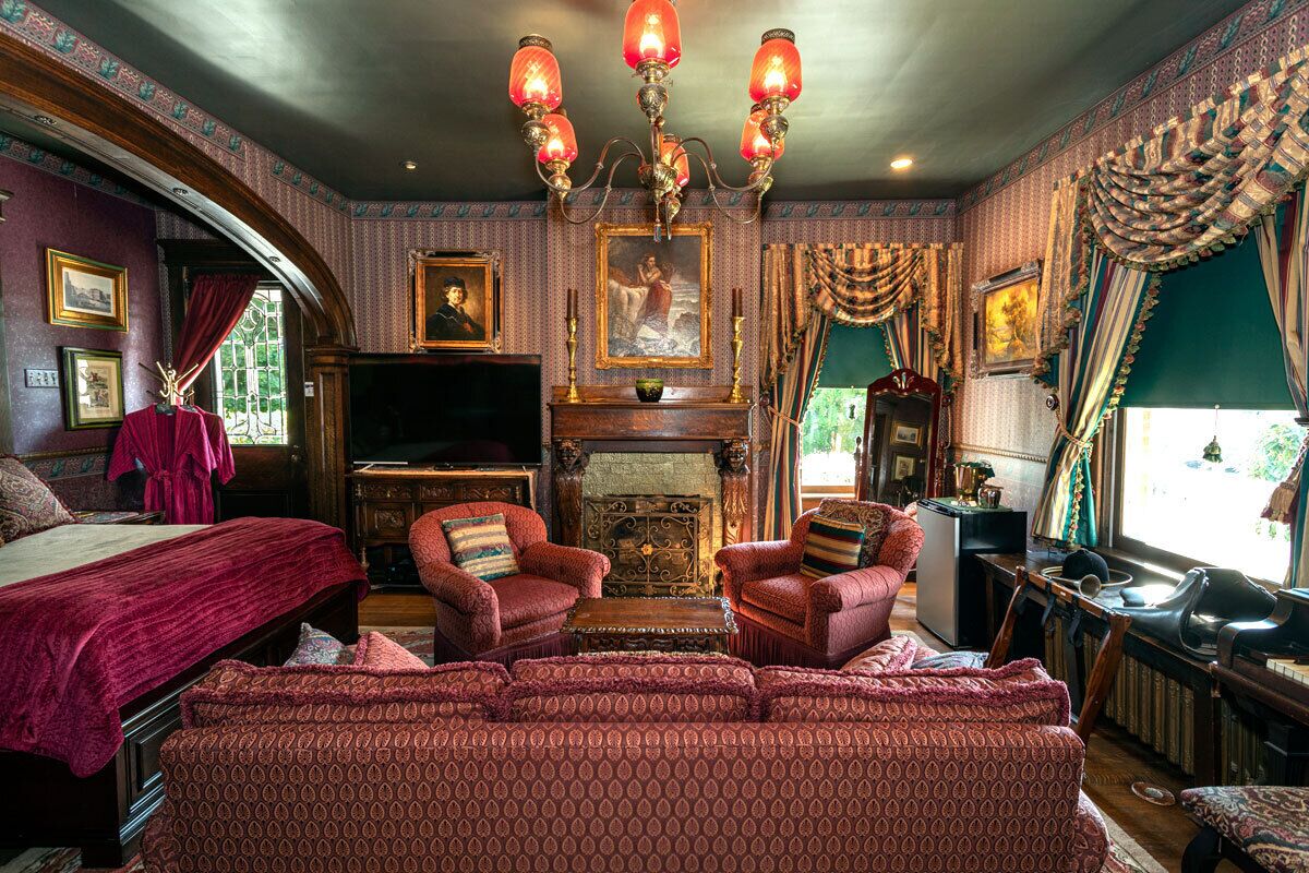 Una habitación tradicional con chimenea, muebles tapizados en rojo y un candelabro.