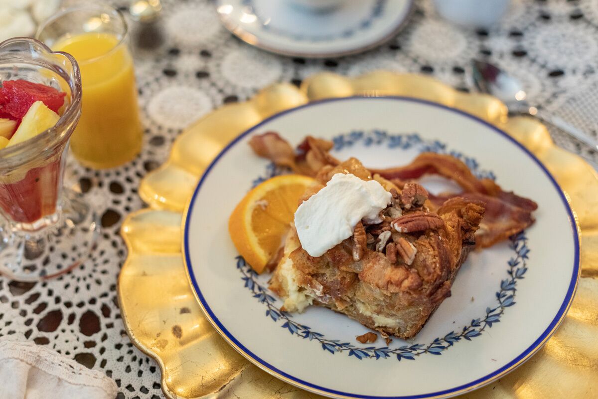 A breakfast plate with bacon, orange, and whipped cream, accompanied by a glass of orange juice.