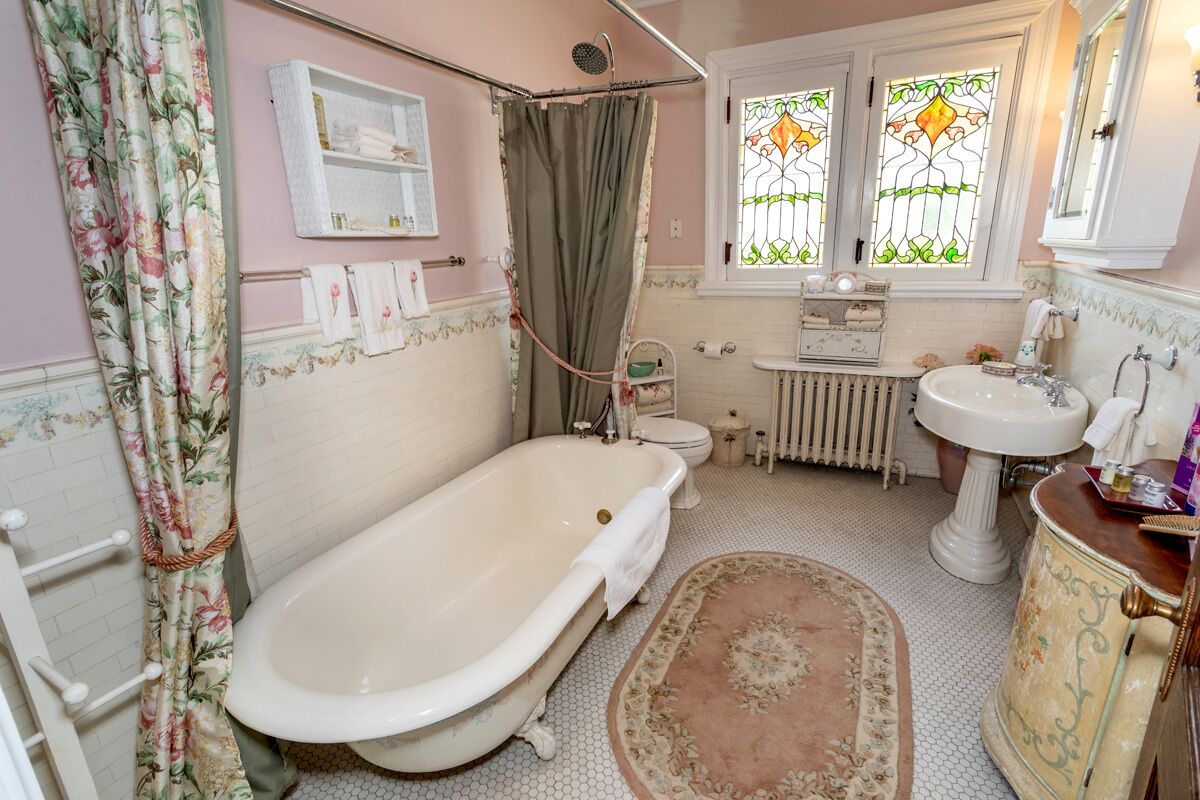 Une salle de bain de style ancien avec une baignoire sur pieds, un lavabo et des toilettes.