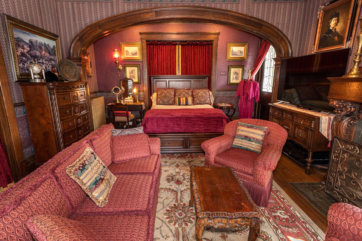 Quarto com uma cama grande, duas poltronas, uma mesa de centro de madeira e uma cômoda.