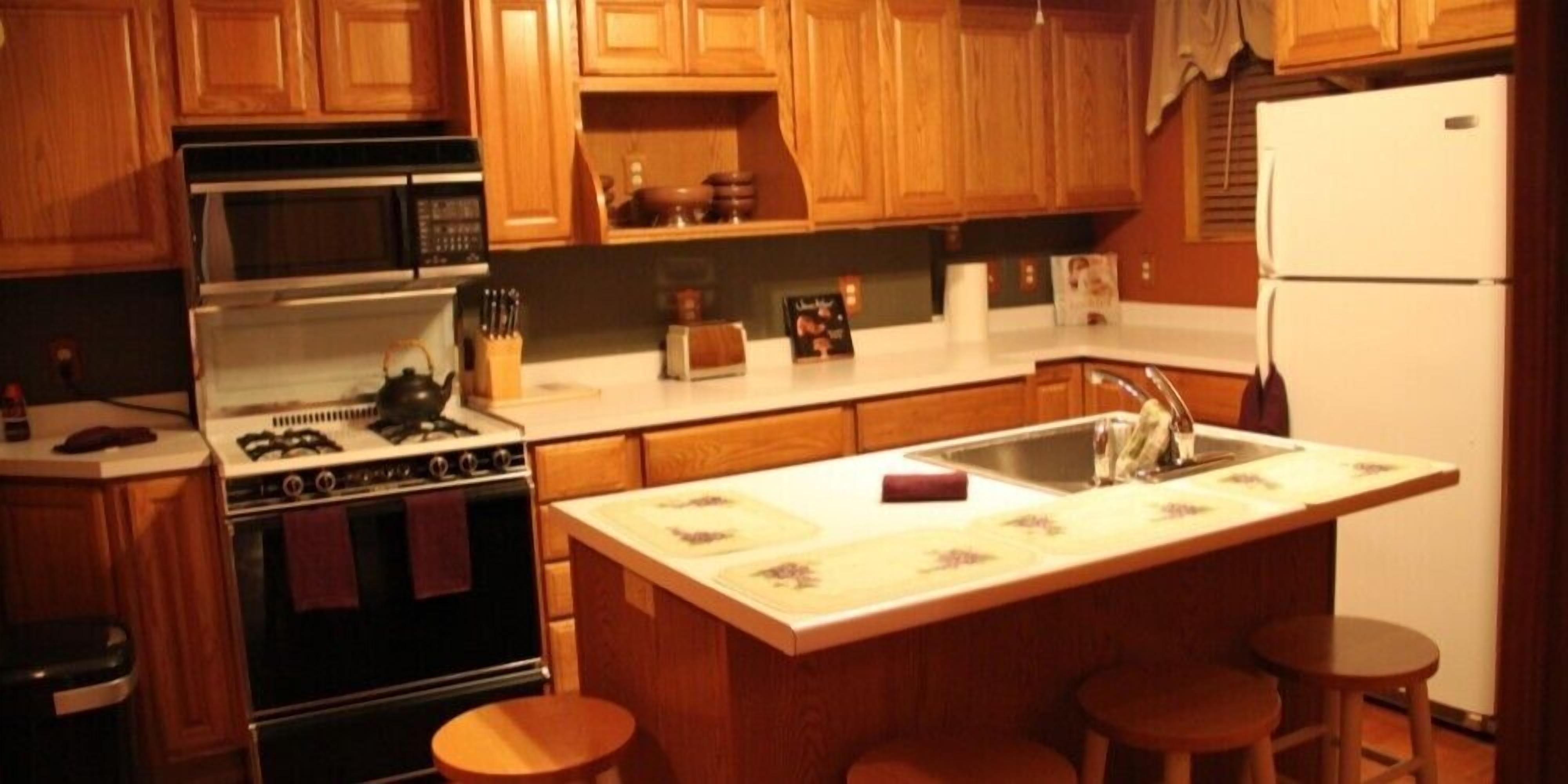 A kitchen with wooden cabinets, a stove, a sink, and a refrigerator.