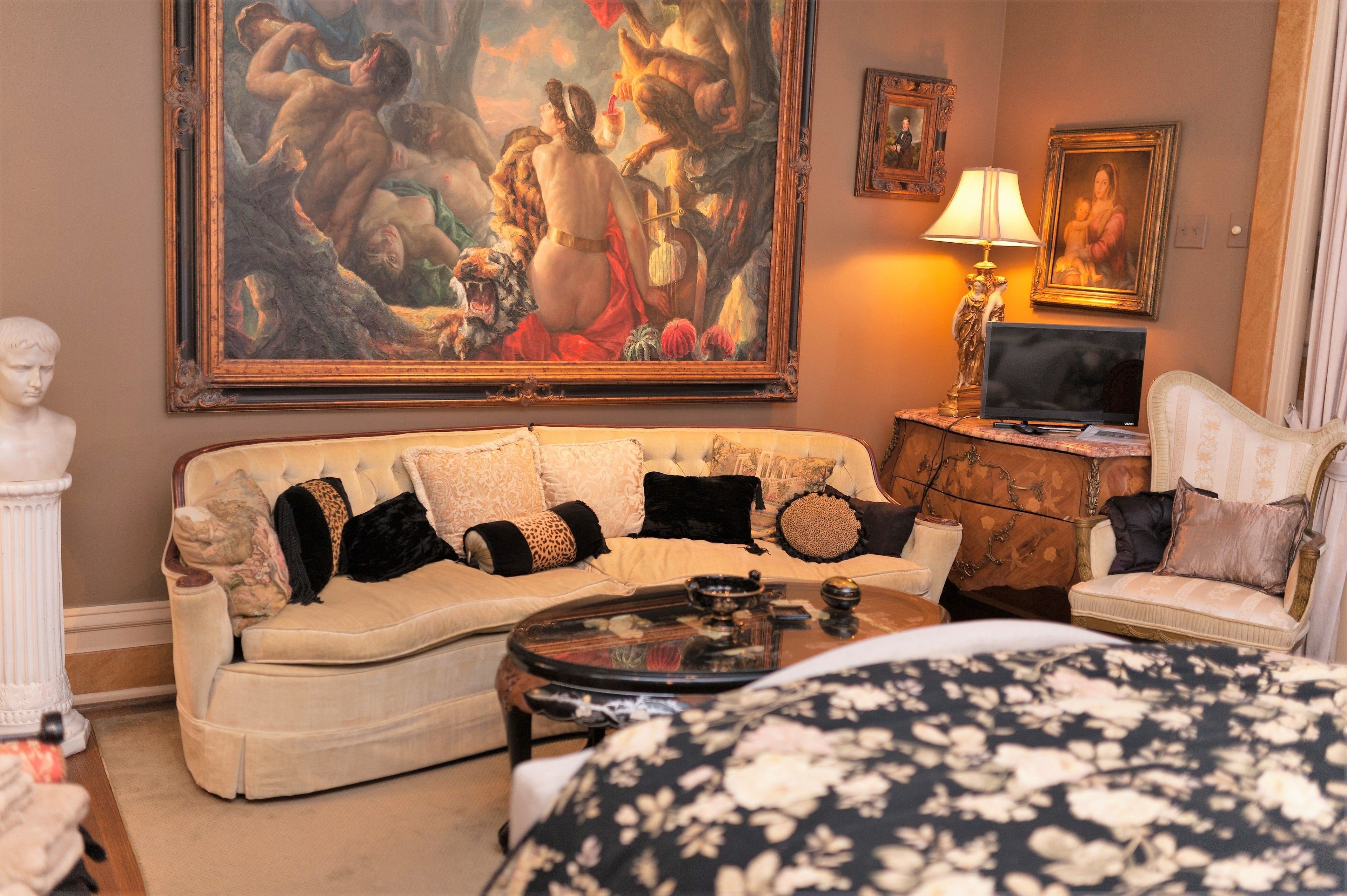 A room with a sofa, a coffee table, a television, and a bed.