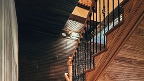 A wooden staircase with a metal railing and a horse statue at the bottom.