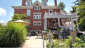 A large brick building with a covered patio area featuring outdoor furniture.