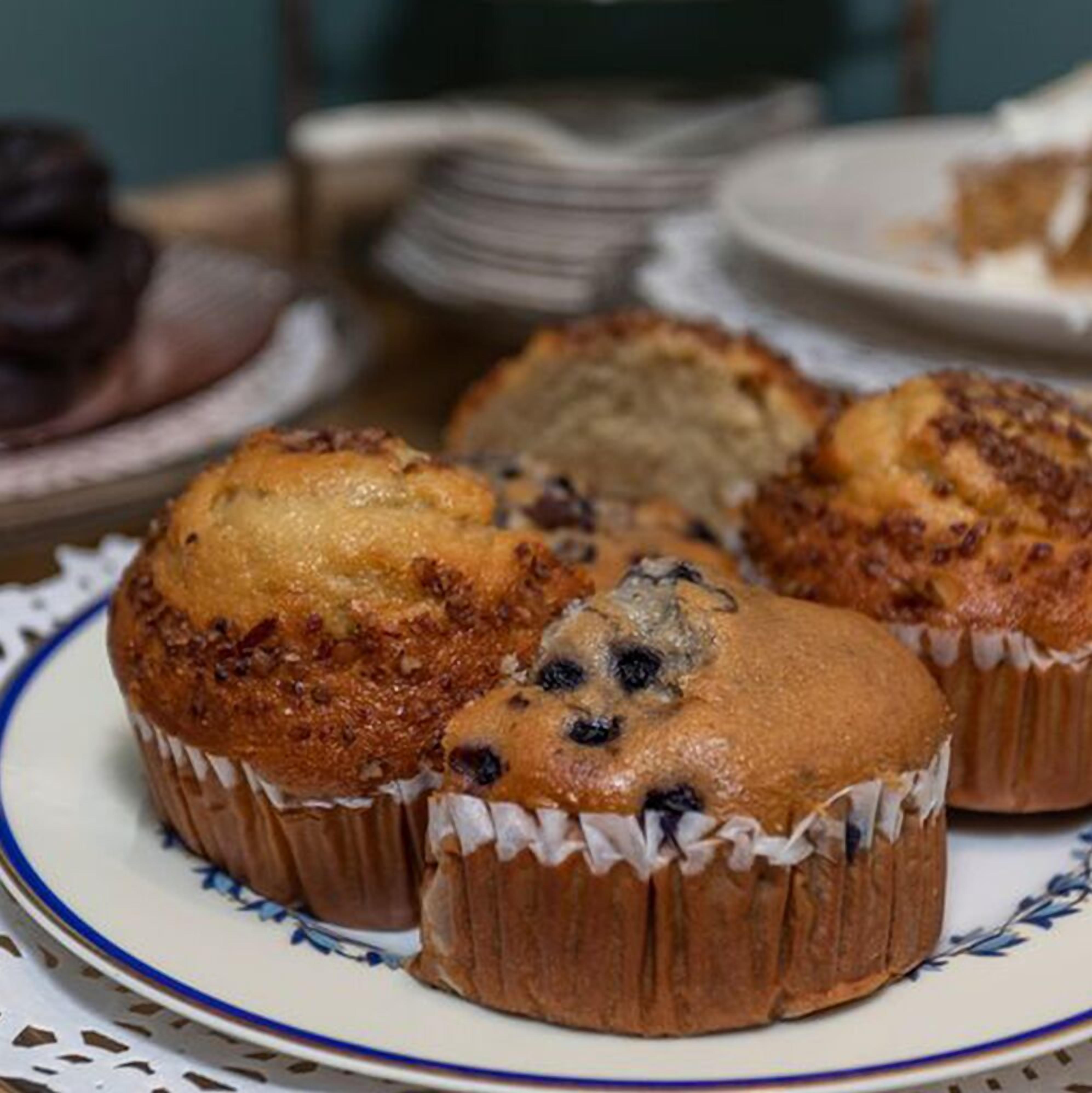 En tallerken med muffins med et blåt og hvidt mønster, placeret på et bord med et blondehvide.