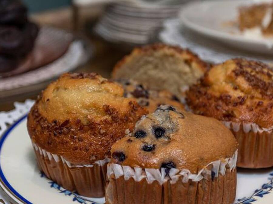 En tallerken med muffins med et blåt og hvidt mønster, placeret på et bord med et blondehvide.