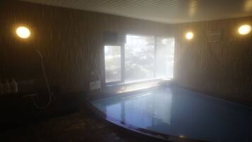 A steam room with a glass enclosure, wooden walls, and a window allowing natural light.