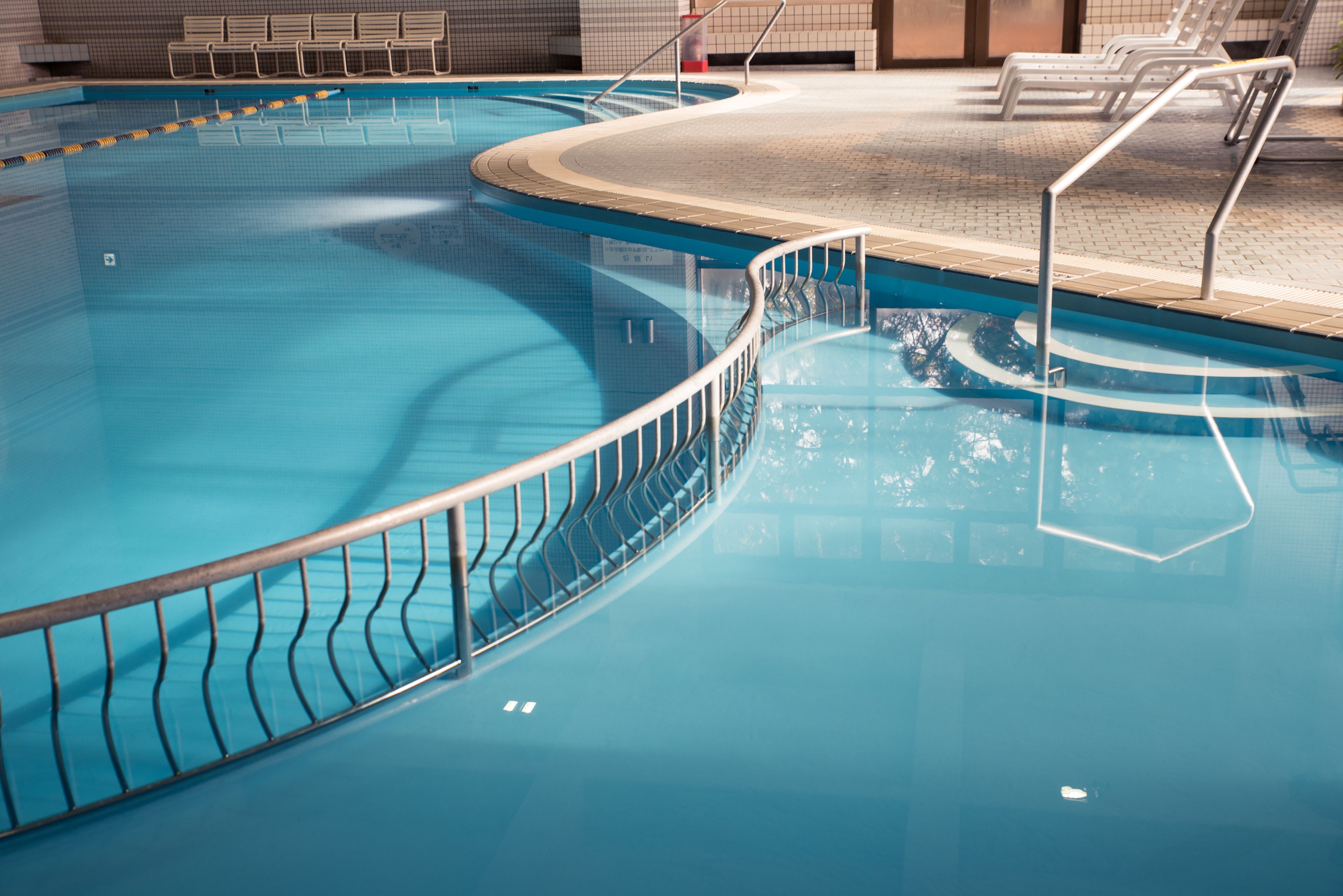An indoor swimming pool with clear water, a curved edge, and a tiled floor.