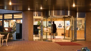 A hotel entrance with a glass door, a reception desk, and a Christmas tree outside. - Wisterian Life Club Verde no Mori (Hakone)