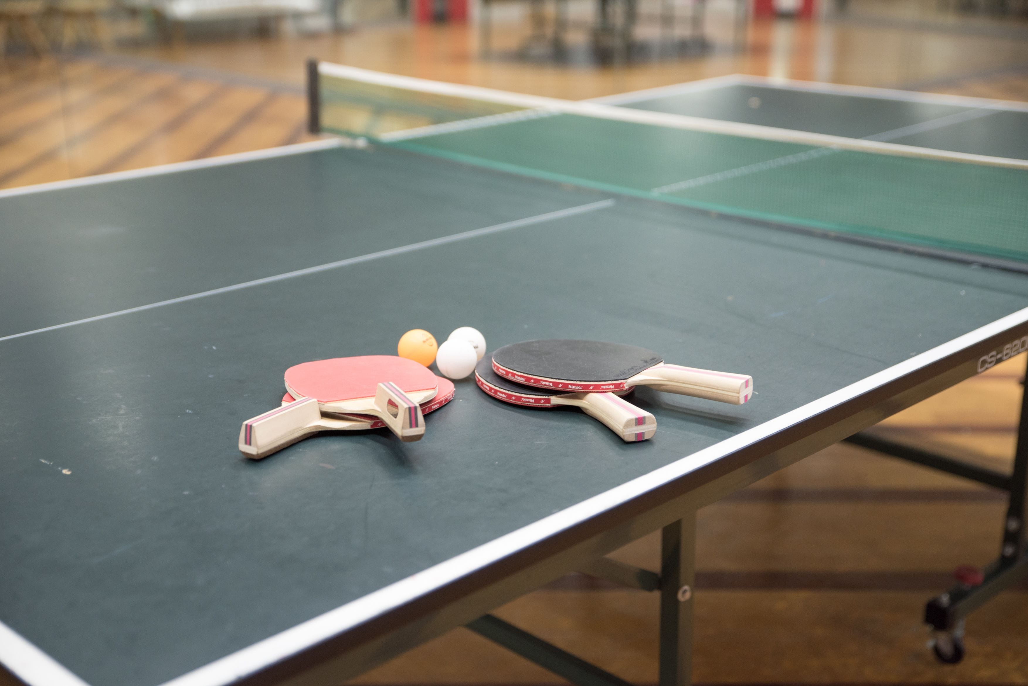 A table tennis table with two paddles, a ball, and a ball paddle.