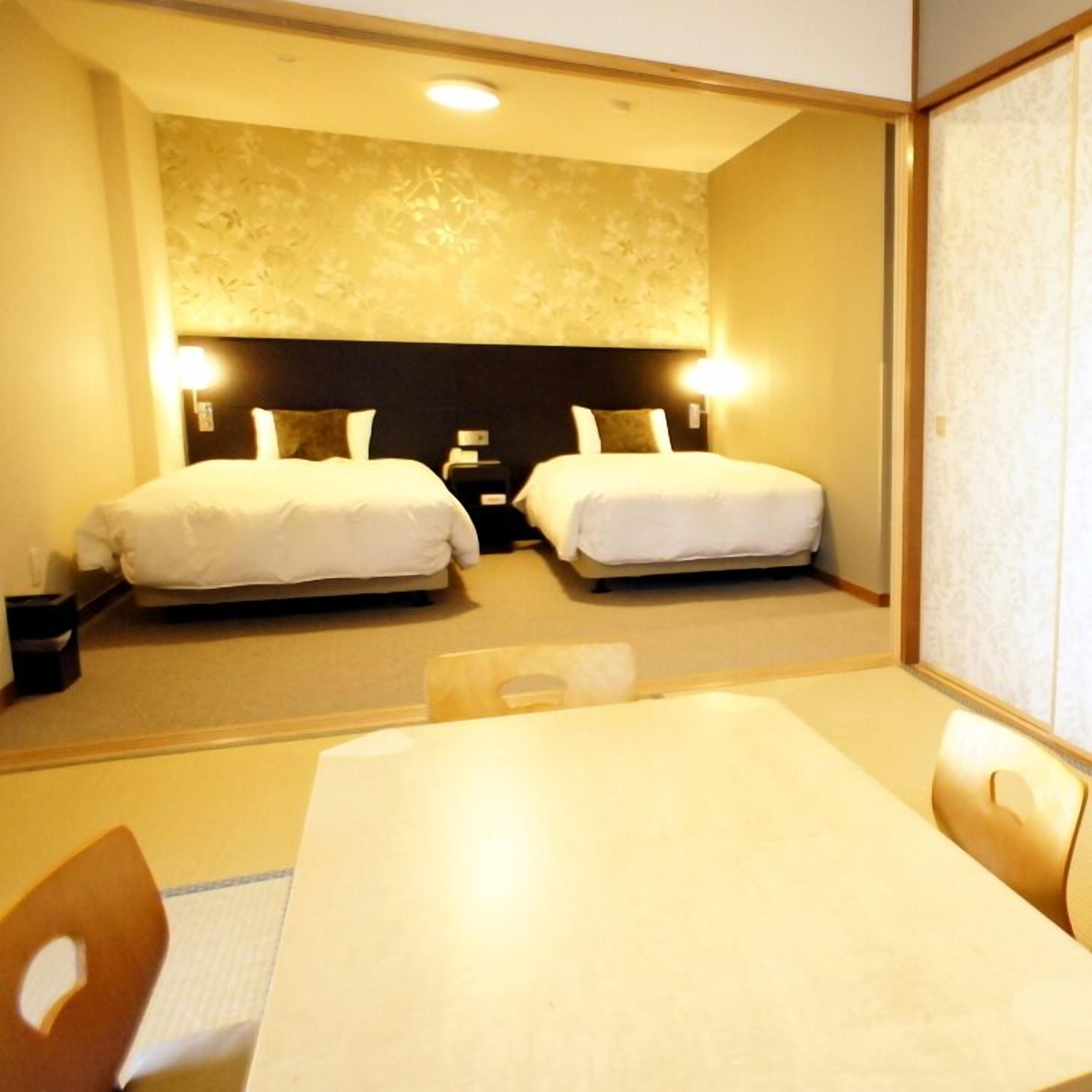 Une chambre d’hôtel avec deux lits, une table et des chaises.
