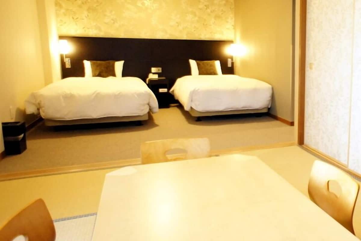 Une chambre d’hôtel avec deux lits, une table et des chaises.