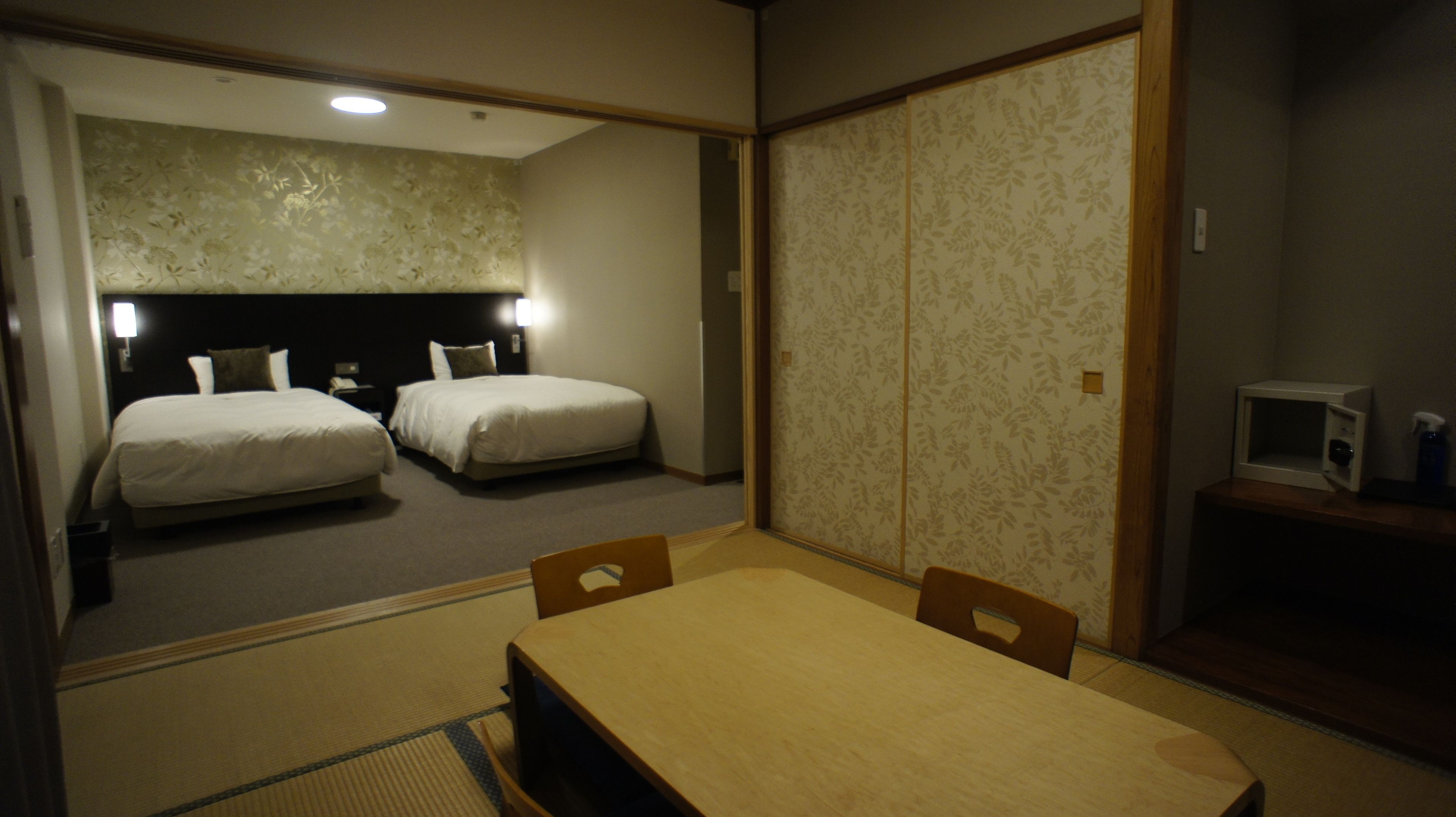 A hotel room with two beds, a wooden table, and a small TV.