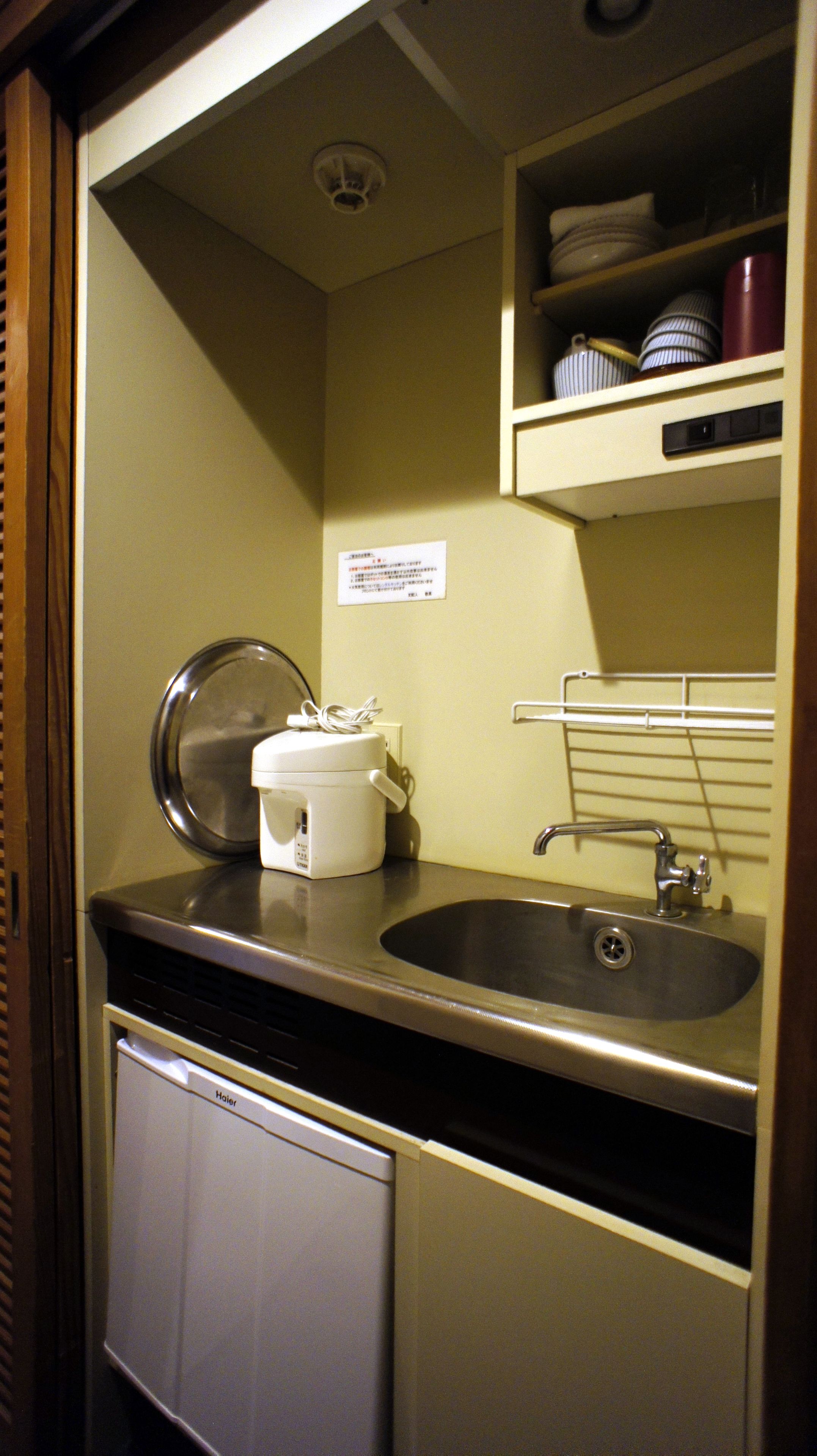 A compact kitchenette with a sink, a coffee maker, and a small refrigerator.