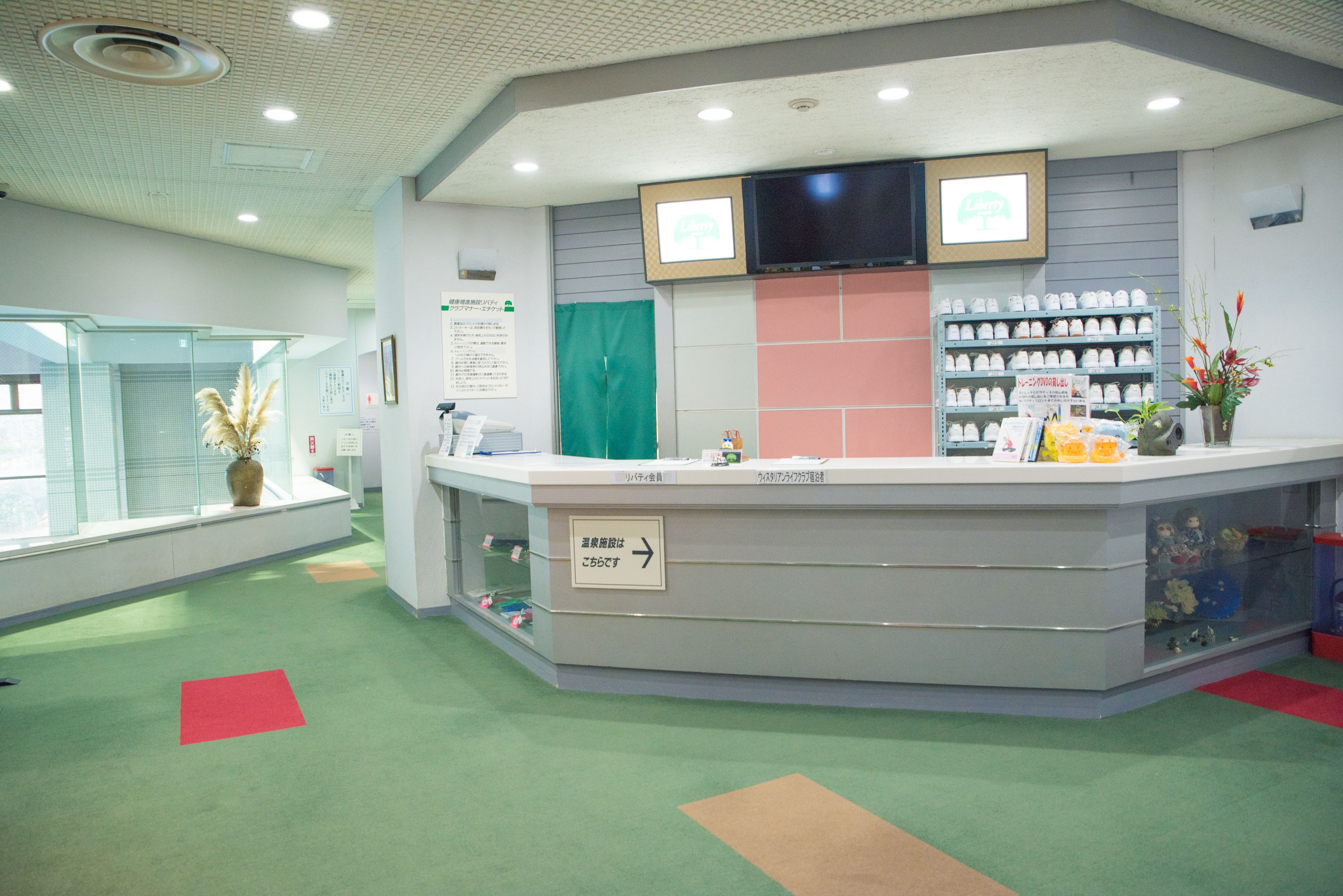 A reception area with a counter, a television mounted above it, and a display of items on shelves.