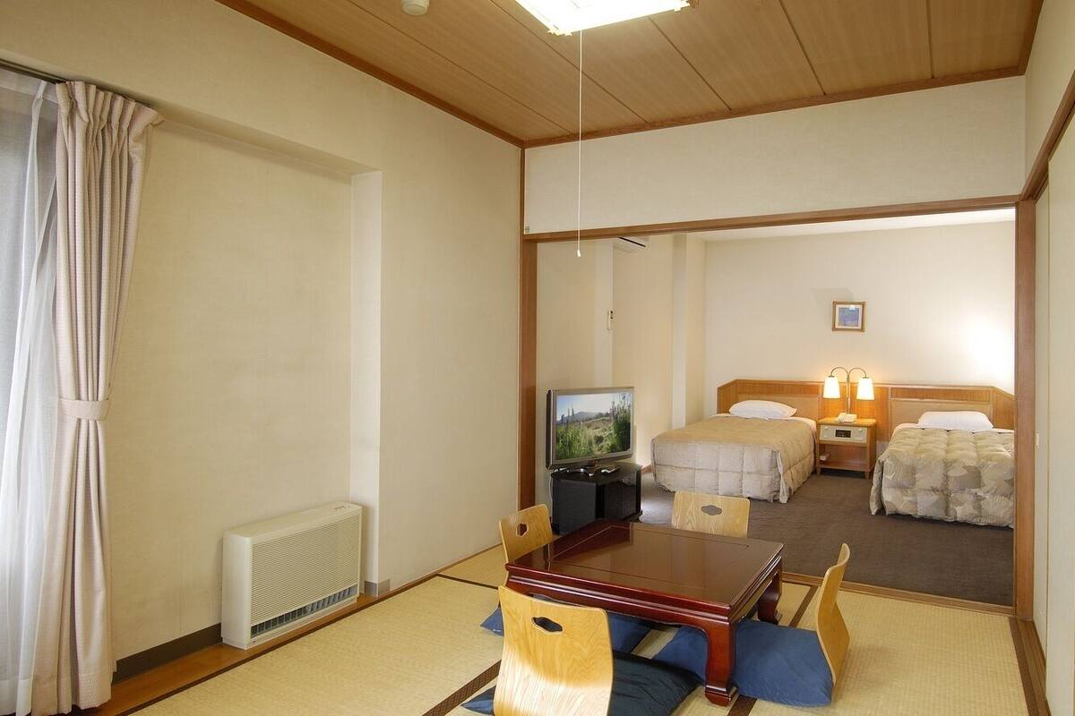 Une chambre d’hôtel avec un plafond en bois, une télévision, une table à manger avec des chaises et deux lits.