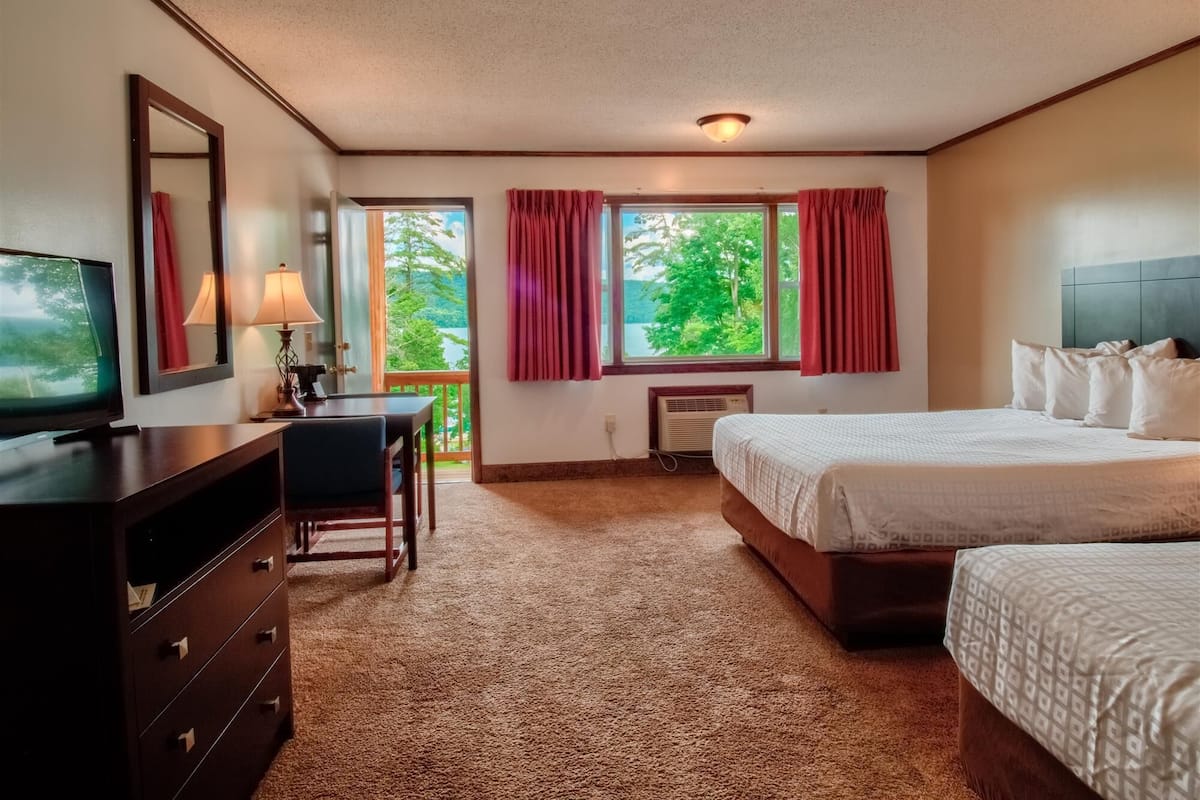 Ein Hotelzimmer mit einem Bett, einem Schreibtisch, einem Fernseher und einem fenster mit Vorhängen.