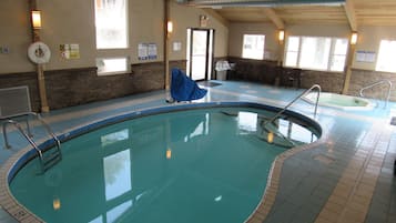 An indoor swimming pool with clear water, surrounded by tiled walls and a wooden ceiling.