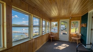 A cabin with large windows overlooking a lake and dock. - Lake 'N Pines Motel (Cooperstown)